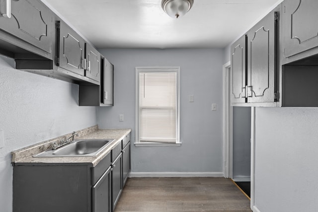 kitchen featuring dark wood-type flooring, gray cabinets, a sink, and light countertops