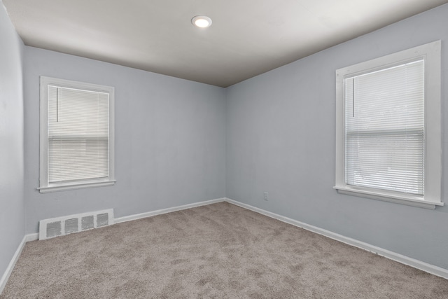 spare room featuring light carpet, baseboards, and visible vents