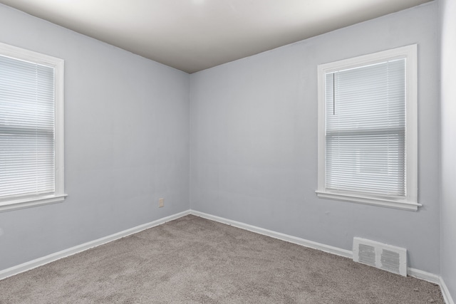 empty room featuring light colored carpet, visible vents, and baseboards