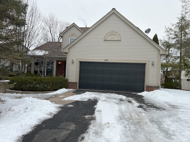 traditional home featuring a garage, brick siding, and driveway