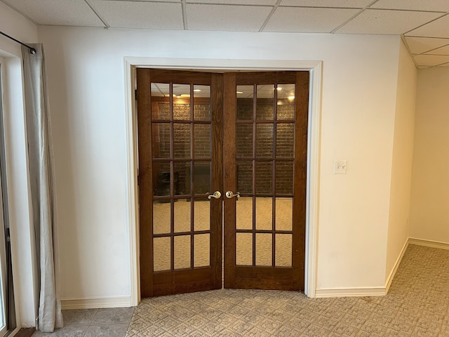 interior space featuring french doors, a paneled ceiling, and baseboards