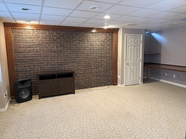 finished below grade area featuring brick wall, carpet, a paneled ceiling, and baseboards