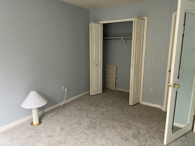 unfurnished bedroom with carpet floors, a closet, and baseboards