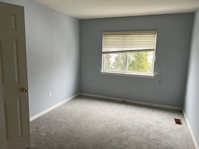 empty room featuring visible vents, baseboards, and carpet flooring