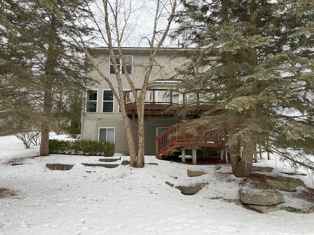 snow covered back of property with a wooden deck