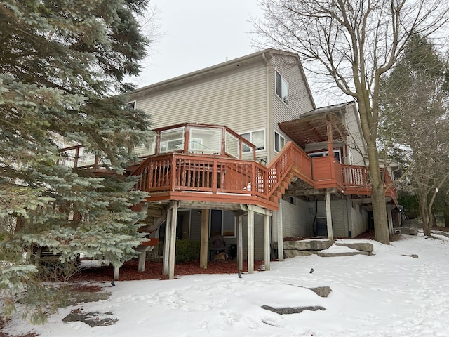 snow covered back of property featuring a deck and stairway