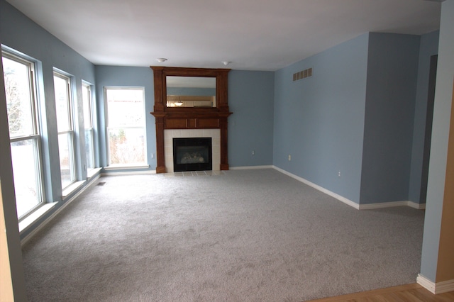 unfurnished living room with carpet, visible vents, a fireplace, and baseboards