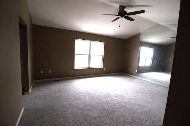 empty room with carpet floors, ceiling fan, baseboards, and vaulted ceiling