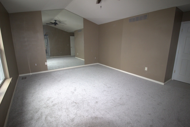 carpeted empty room with lofted ceiling, baseboards, visible vents, and a ceiling fan