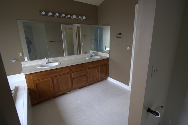 bathroom featuring double vanity, baseboards, and a sink