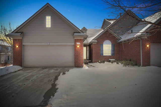 traditional-style house featuring an attached garage, driveway, and brick siding