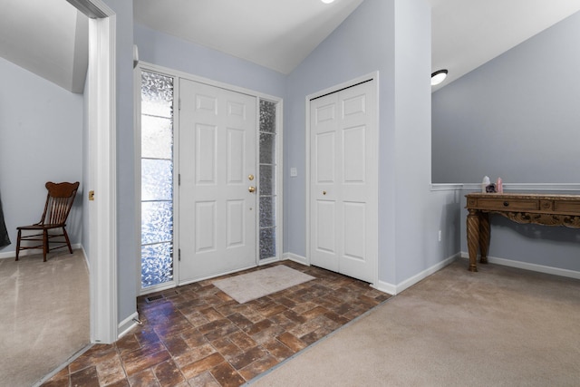 entryway with lofted ceiling, dark carpet, and baseboards