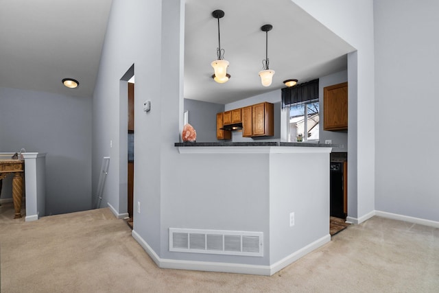 kitchen featuring brown cabinets, dark countertops, visible vents, hanging light fixtures, and a peninsula