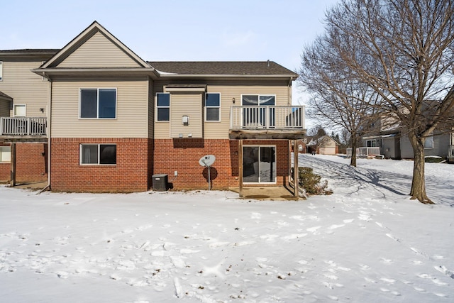 view of front of home featuring brick siding, a balcony, and central air condition unit