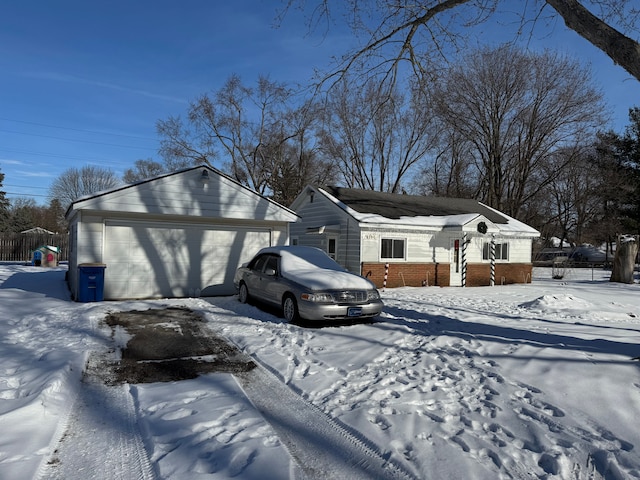 view of front of property with brick siding, a detached garage, and fence