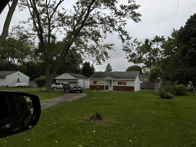 ranch-style home with an outbuilding, driveway, a front lawn, and fence