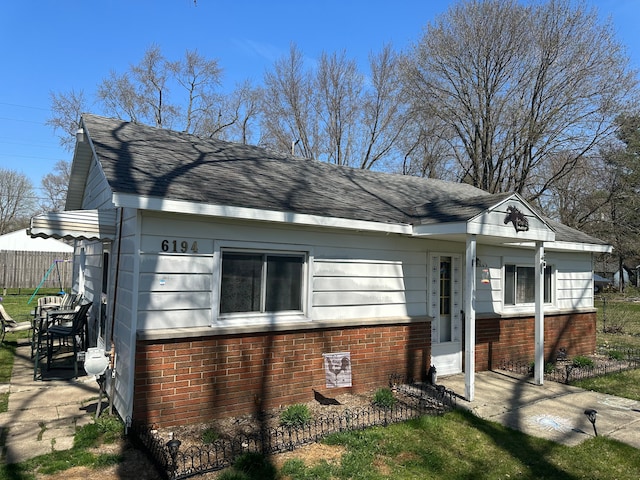 view of front facade with a shingled roof and brick siding