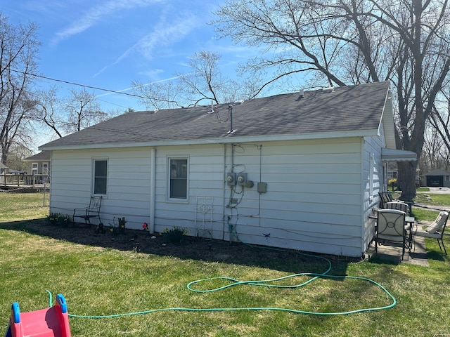 view of side of home with a shingled roof and a yard