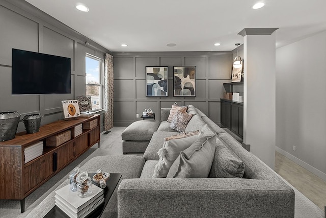 living room featuring recessed lighting, a decorative wall, and baseboards