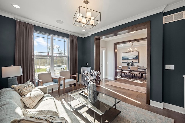 living room featuring recessed lighting, wood finished floors, baseboards, an inviting chandelier, and crown molding