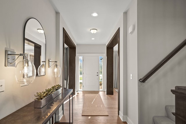 foyer featuring baseboards, stairway, wood finished floors, and recessed lighting