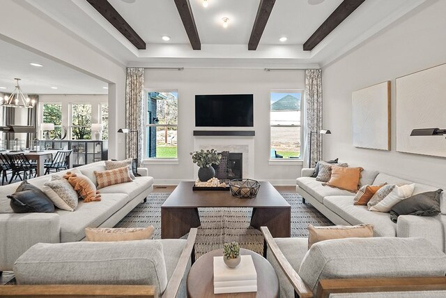 living room with a chandelier, a fireplace, beam ceiling, and baseboards