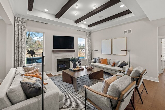 living area with light wood-style flooring, beamed ceiling, plenty of natural light, and visible vents