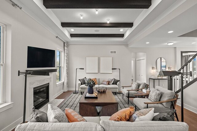 living area with stairway, beamed ceiling, a fireplace, and a wealth of natural light