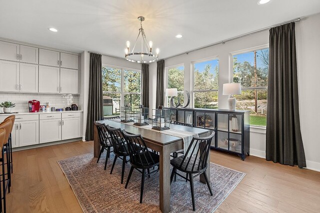 dining area with recessed lighting, light wood finished floors, and an inviting chandelier