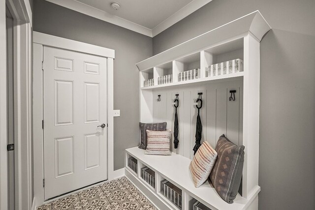 mudroom with light tile patterned floors, ornamental molding, and baseboards