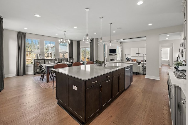 kitchen with pendant lighting, a large island, light countertops, open floor plan, and a sink