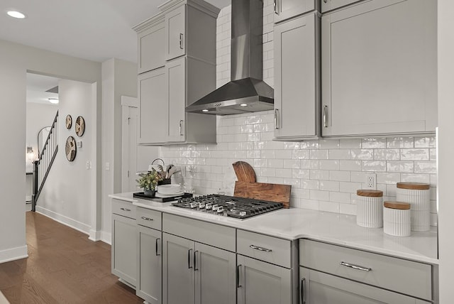 kitchen with wall chimney range hood, stainless steel gas stovetop, light countertops, and gray cabinetry