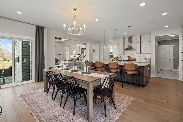 dining room with stairs, light wood finished floors, a chandelier, and recessed lighting
