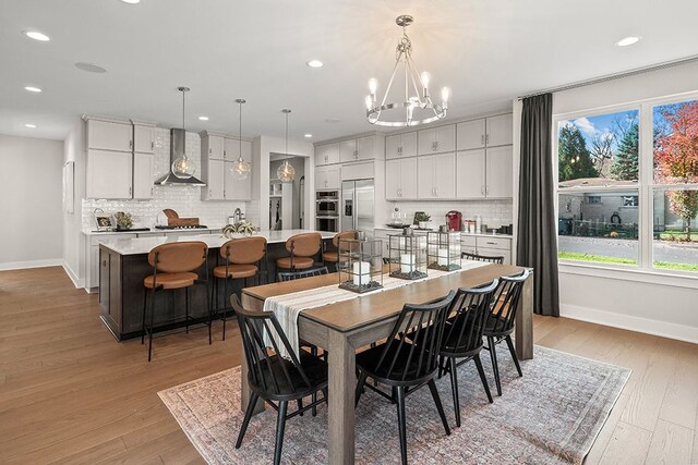 dining area featuring baseboards, recessed lighting, a notable chandelier, and light wood-style floors