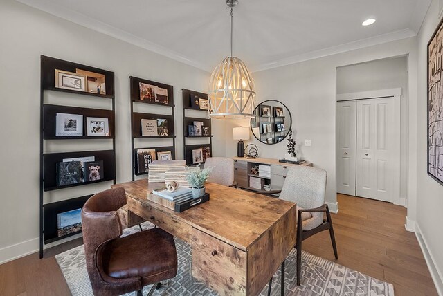 office with baseboards, a notable chandelier, wood finished floors, and crown molding