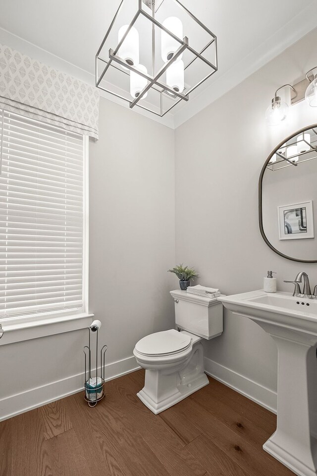 bathroom with an inviting chandelier, toilet, baseboards, and wood finished floors
