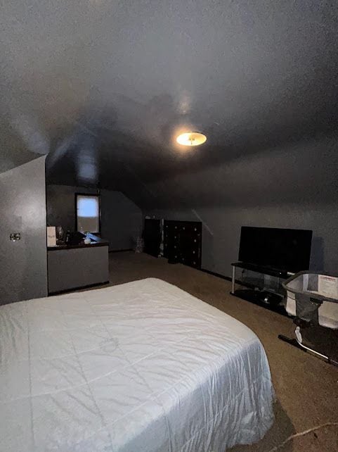 carpeted bedroom with vaulted ceiling and a textured ceiling