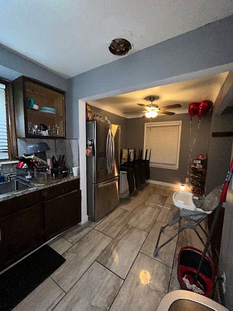 kitchen featuring dark brown cabinetry, a sink, freestanding refrigerator, and a ceiling fan