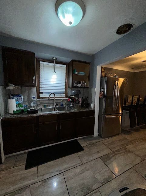 kitchen featuring backsplash, a sink, freestanding refrigerator, and dark brown cabinetry