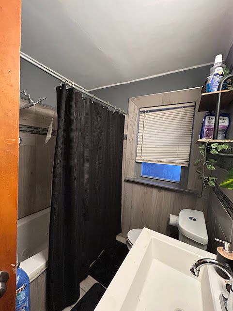 bathroom with toilet and shower / bathtub combination with curtain