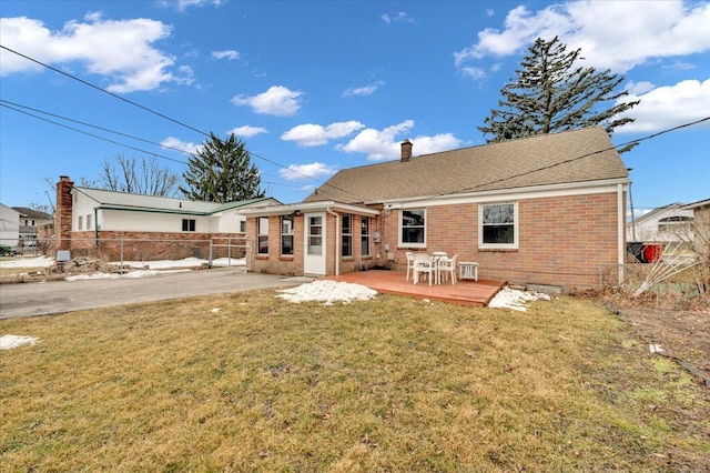 rear view of property with a wooden deck, a chimney, fence, a yard, and brick siding