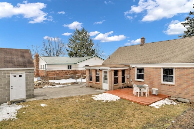 rear view of house featuring brick siding, roof with shingles, a chimney, fence, and a wooden deck