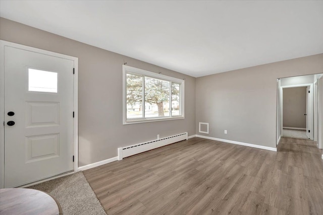 foyer featuring baseboard heating, wood finished floors, and baseboards