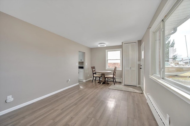 dining space featuring baseboard heating, light wood-style flooring, and baseboards