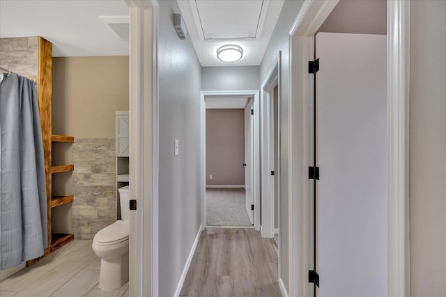 interior space with light wood-style floors, attic access, and baseboards