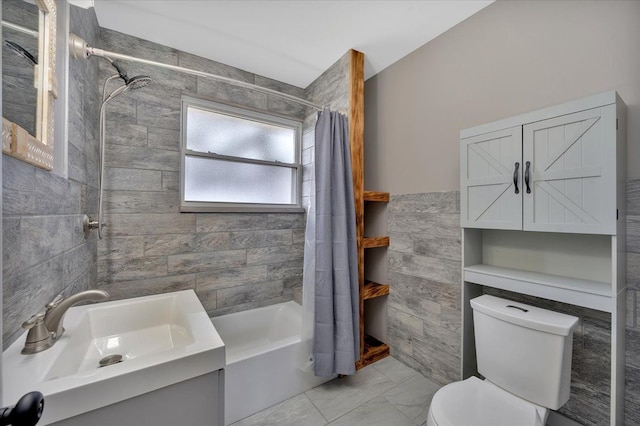 bathroom featuring marble finish floor, tile walls, shower / bathtub combination with curtain, toilet, and a sink