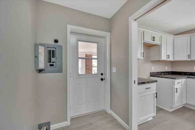 kitchen featuring light wood-style floors, electric panel, baseboards, and white cabinetry