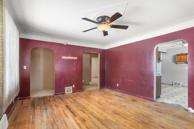 spare room with a ceiling fan, arched walkways, and visible vents