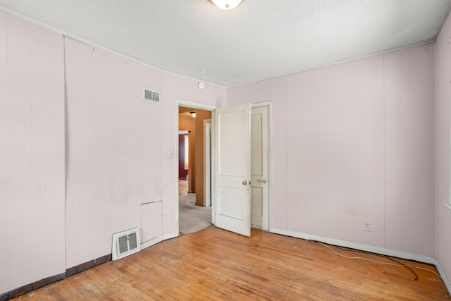 unfurnished room featuring wood-type flooring and visible vents