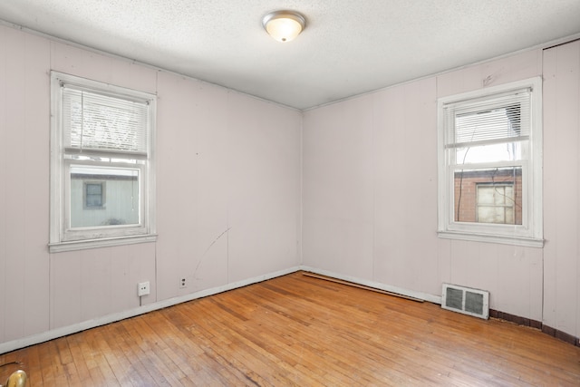 spare room featuring a wealth of natural light, wood-type flooring, and visible vents